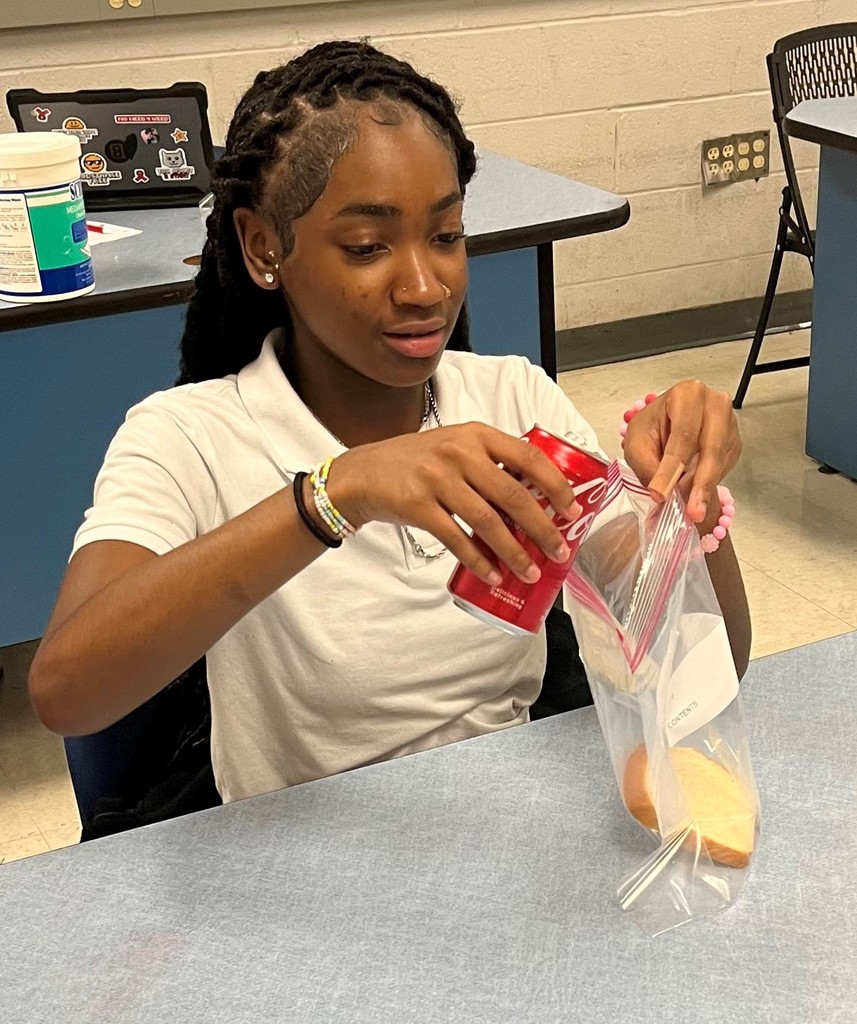 Agriculture student pouring soda into a bag to simulate the digestive system.