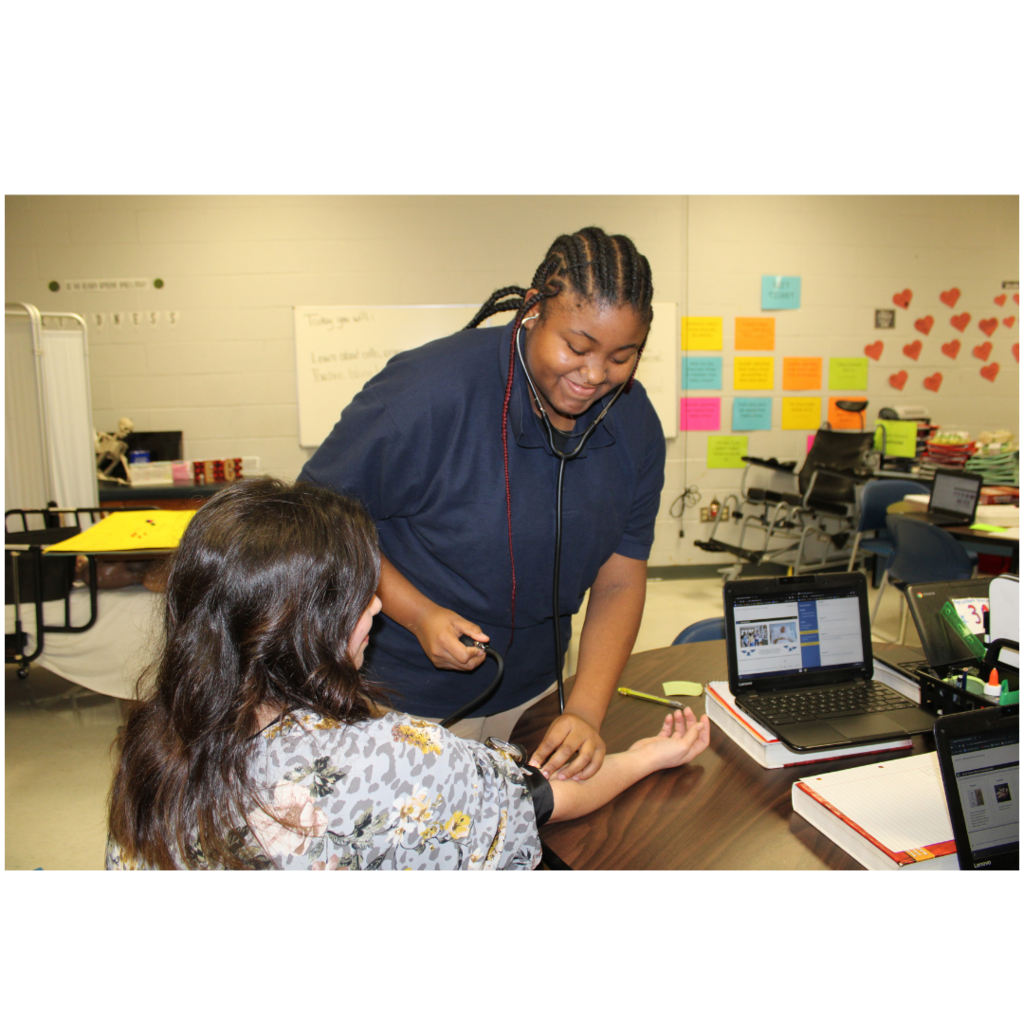 A health science student taking Ms. Brock's blood pressure. 