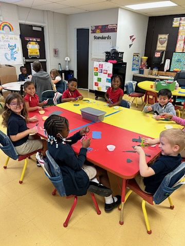 kinder students cutting paper at a table