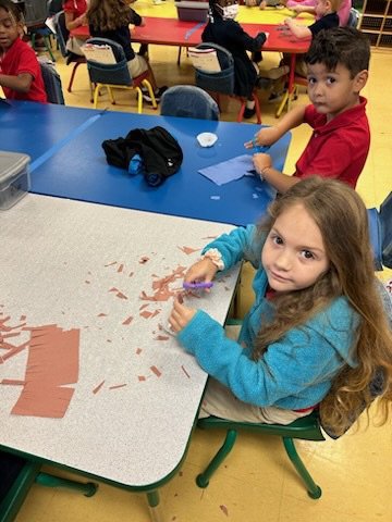 kinder student sitting and cutting paper